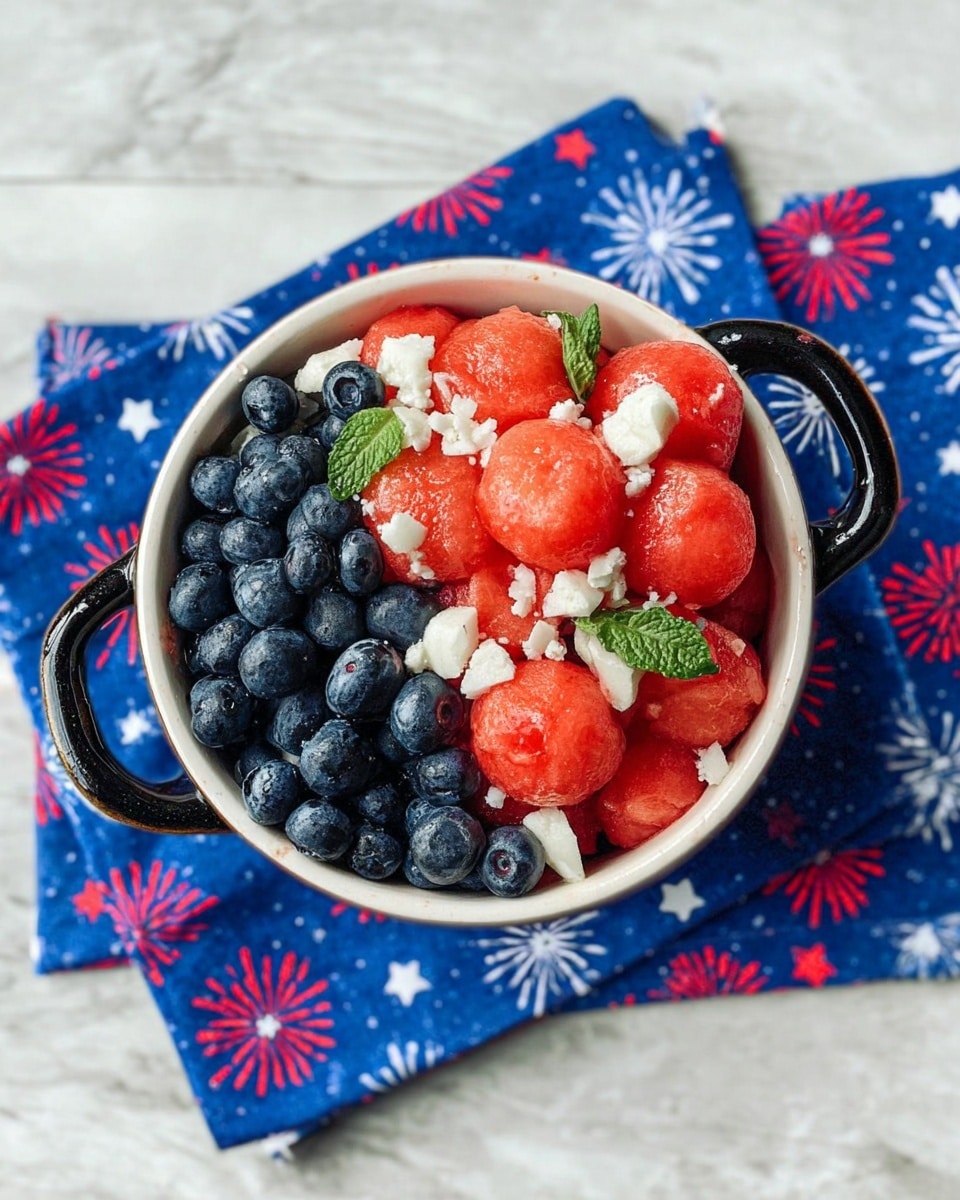 A white bowl with black handles is filled with three layers of ingredients: the bottom layer consists of small, dark blueberries; the middle layer has larger, bright red watermelon balls with a juicy texture; scattered on the top are small chunks of white cheese and a few green mint leaves, adding color contrast and freshness. The bowl sits on a blue cloth with red and white firework patterns, all placed on a white marbled surface. photo taken with an iphone --ar 4:5 --v 7