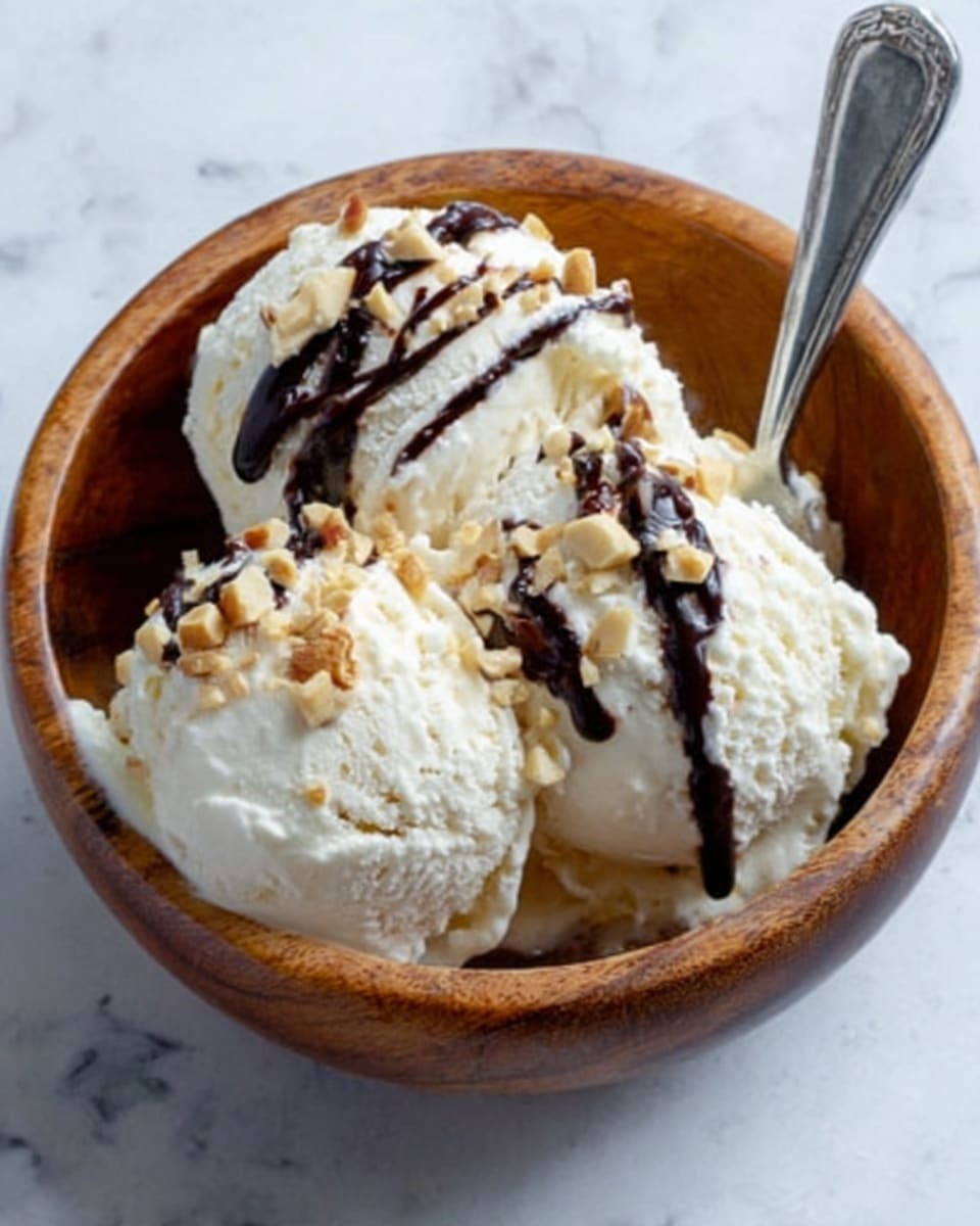 A wooden bowl filled with three scoops of creamy vanilla ice cream, topped with a drizzle of dark chocolate sauce and sprinkled with small pieces of chopped nuts. A silver spoon rests inside the bowl on the right side. The bowl is placed on a white marbled surface. Photo taken with an iphone --ar 4:5 --v 7