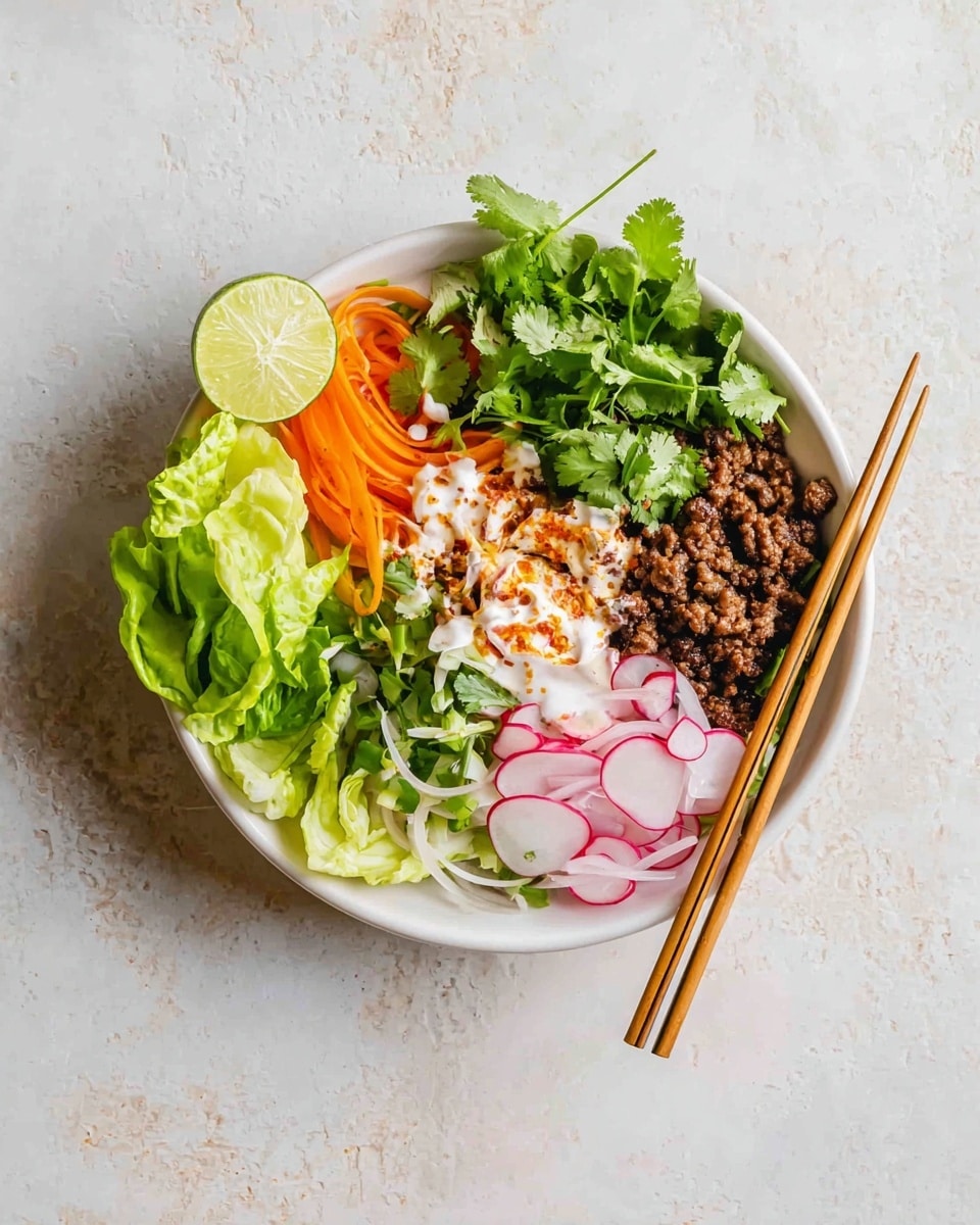 A white bowl filled with layered food sits on a white marbled surface. At the base, there are fresh green lettuce wedges on the right side, topped lightly with creamy white sauce and a dash of paprika. Next to the lettuce, cooked dark brown ground meat forms a thick layer. On top of the meat, small bright orange carrot slices are scattered with white sauce drizzled over. Thinly sliced white and purple onions rest at the front bottom left, near a bunch of fresh cilantro on the right edge. Radish slices with pink edges and green stems are placed next to the meat on the left side. A wedge of yellow lemon is tucked on the right near the cilantro. Black chopsticks rest inside the bowl at the bottom left. The overall image has natural light, showing fresh textures in all layers. Photo taken with an iphone --ar 4:5 --v 7