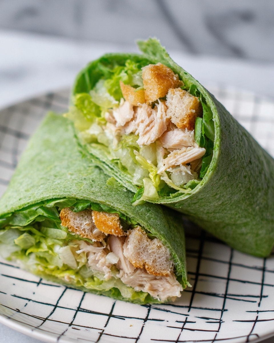 A close-up of two halves of a green tortilla wrap placed on a white plate with a black grid pattern, lying on a white marbled surface. The wrap is cut to show three main layers inside: the soft green tortilla on the outside, followed by a layer of light green leafy lettuce, crispy golden-brown croutons, and shredded pale beige chicken pieces. The textures contrast with the soft tortilla, crunchy croutons, and moist chicken, all fitting tightly together. photo taken with an iphone --ar 4:5 --v 7
