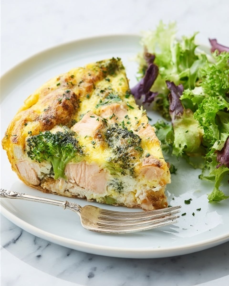 A slice of pie with visible layers is shown on a white plate. The bottom layer is light and smooth, covered by a thick creamy layer featuring chunks of pink salmon and green broccoli pieces. The top part is golden brown with a slightly crispy look and sprinkled with green herbs. Next to the pie slice, there is a small portion of fresh mixed green leaves. A silver fork rests on the left side of the plate. The plate is placed on a white marbled surface. Photo taken with an iphone --ar 4:5 --v 7