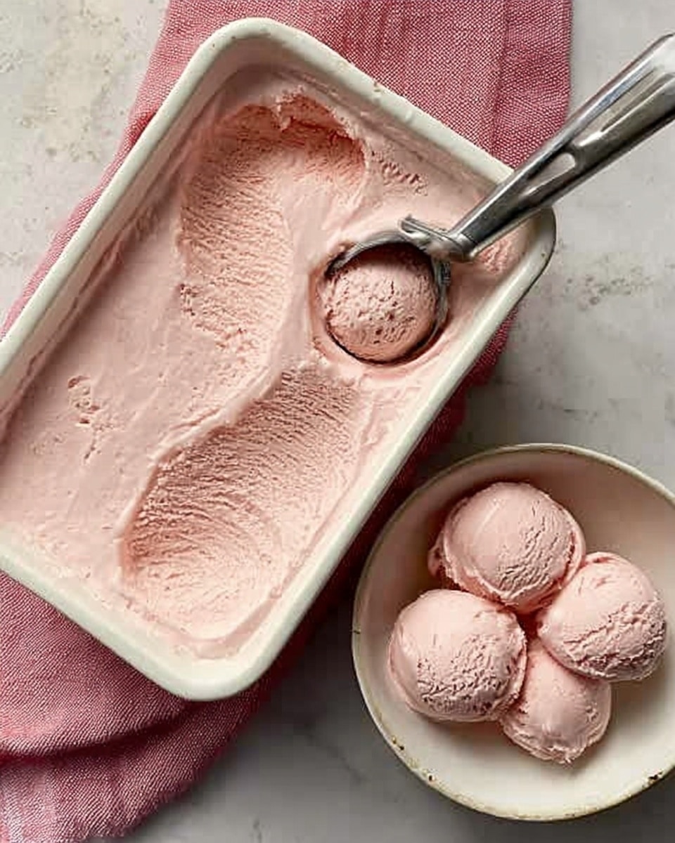 A white rectangular baking dish filled with a smooth, light pink ice cream that has a soft, creamy texture. A metal ice cream scoop rests on the dish, holding a rounded scoop of the same pink ice cream. Nearby, a white bowl contains three scoops of the pink ice cream, each with a slightly rough texture. The dishes sit on a white marbled surface, and a woman's hand is about to scoop more ice cream. The overall scene looks simple and fresh. photo taken with an iphone --ar 4:5 --v 7