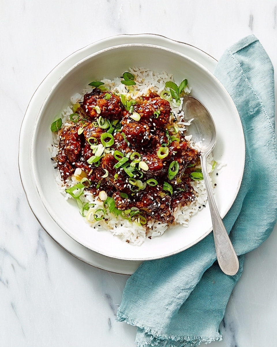 A white bowl filled with a layered dish sits on a white plate, placed on a white marbled surface. The bottom layer in the bowl consists of white rice with a fluffy texture. On top of the rice, there is a thick layer of brown minced meat mixed with herbs and spices, giving it a crumbly texture. Small green pieces of chopped spring onions are scattered over the meat, adding a fresh touch of color. A silver spoon rests inside the bowl, and a soft blue cloth napkin is casually draped next to the plate. photo taken with an iphone --ar 4:5 --v 7
