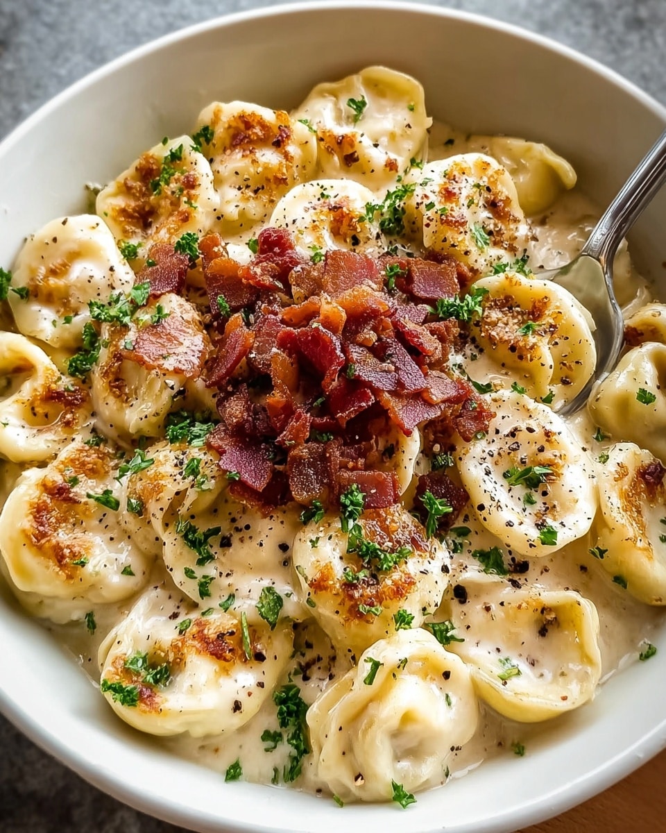 A white bowl filled with tortellini pasta covered in creamy sauce, with the pasta rings showing a pale yellow color and slightly toasted edges. On top, there is a generous layer of crispy, dark reddish-brown bacon bits and bright green finely chopped parsley sprinkled all over. The creamy sauce underneath has a smooth texture, with some browned specks possibly from grated cheese and black pepper giving a textured look. A silver fork is placed on the right side inside the bowl, resting on the pasta. The bowl is set on a white marbled surface. Photo taken with an iphone --ar 4:5 --v 7