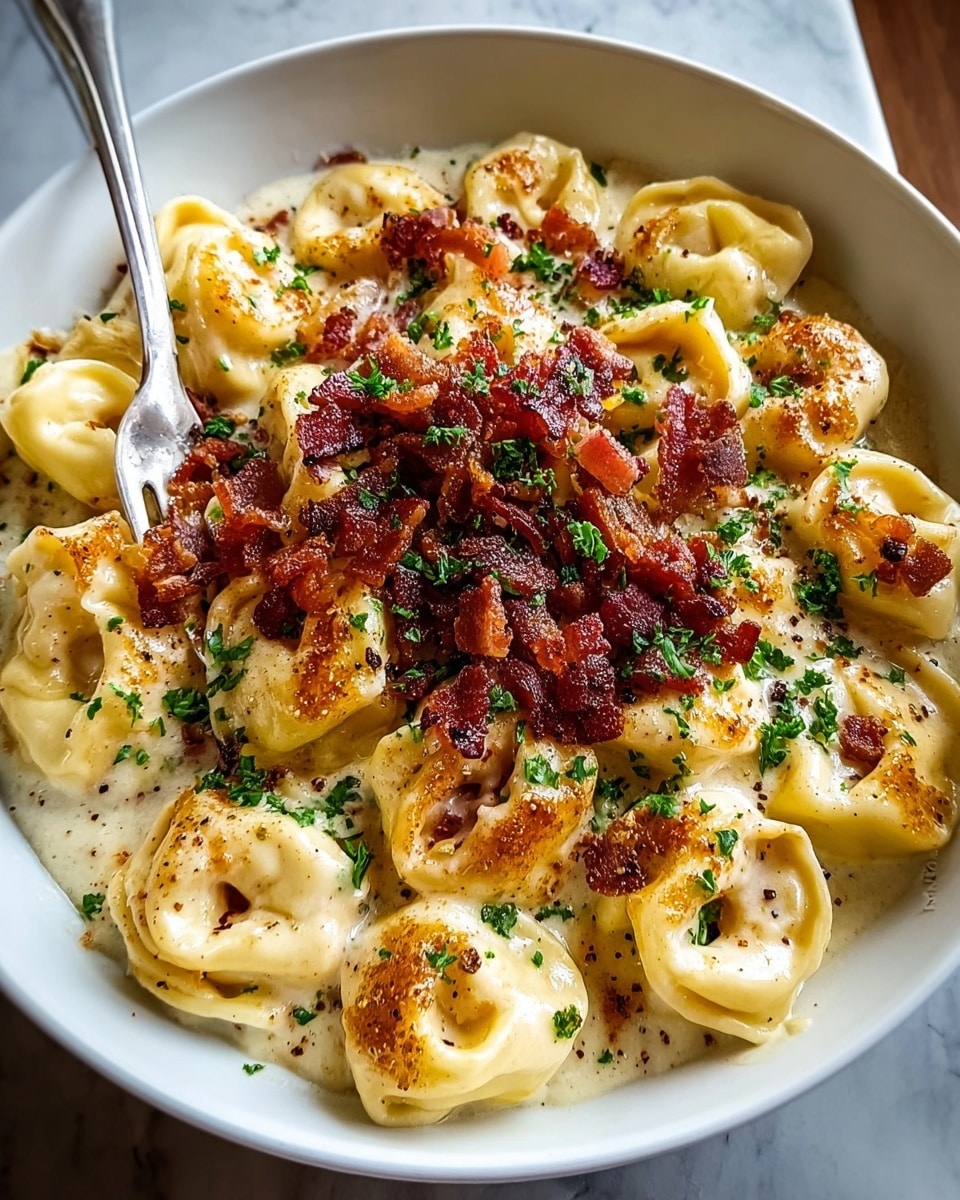 A white bowl filled with a single layer of round tortellini pasta covered in creamy white sauce, browned slightly on top, creating a light golden caramelized texture. The tortellini are evenly coated and arranged in a circular pattern, with a generous pile of crispy diced reddish-brown bacon pieces stacked in the center. Finely chopped green parsley is sprinkled all over, adding a fresh contrast, along with a dusting of finely grated pale white Parmesan cheese and cracked black pepper scattered on top. A silver fork rests against the side inside the bowl on a white marbled surface. photo taken with an iphone --ar 4:5 --v 7