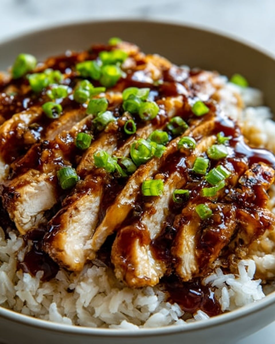 A close-up image of a bowl filled with white rice at the bottom, topped with several thick slices of grilled chicken that have a shiny, dark brown sauce drizzled over them, creating a rich glaze effect. The chicken pieces have a slightly crispy texture on the outside with a tender look inside. Bright green chopped scallions are sprinkled evenly over the chicken, adding a fresh pop of color. The bowl is white and rests on a white marbled surface. The lighting highlights the glossiness of the sauce and the freshness of the scallions, making the dish look appetizing and well-prepared. Photo taken with an iphone --ar 4:5 --v 7