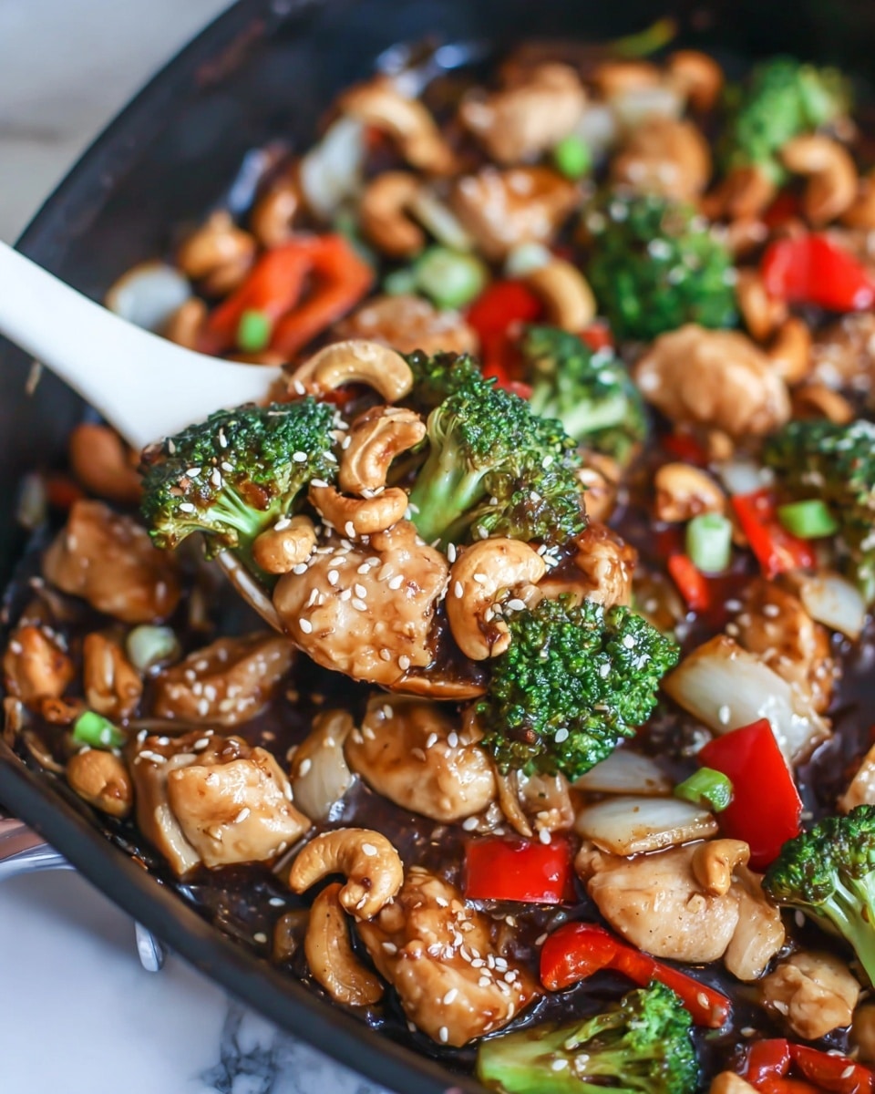 The image shows a close-up of a stir-fry dish in a black pan. The dish has several layers: the bottom layer is a dark brown glossy sauce spreading across the pan's surface. On top of this are chunks of golden-brown cooked chicken, sprinkled with white sesame seeds. Scattered around are bright green broccoli florets, red bell pepper pieces, and translucent cooked onion slices. Light golden cashew nuts are spread evenly throughout the dish. Small pieces of green onion add a fresh touch over the top. A white spoon is scooping some of the stir-fry, showing a mix of chicken, red bell pepper, and broccoli. The background is a white marbled texture. photo taken with an iphone --ar 4:5 --v 7