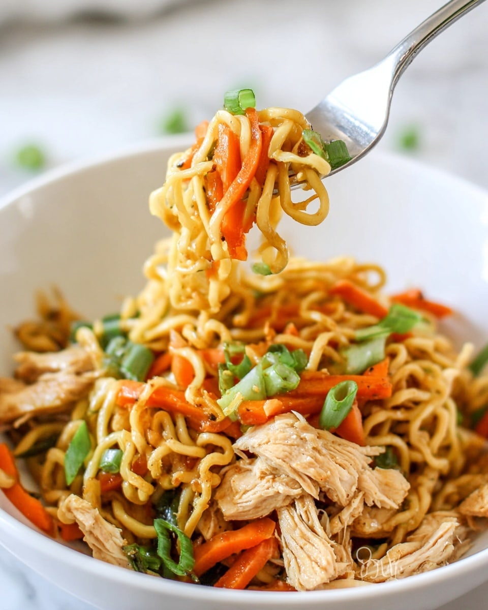 A close-up of a white bowl filled with stir-fried noodles mixed with thin strips of cooked chicken, bright orange julienned carrots, chopped red bell peppers, and small pieces of green onion scattered on top. The noodles are light yellow and curly, slightly glossy from the sauce. A fork holding a small bundle of noodles, carrots, and a green onion slice is lifted above the bowl. The background is a soft white marbled texture. photo taken with an iphone --ar 4:5 --v 7