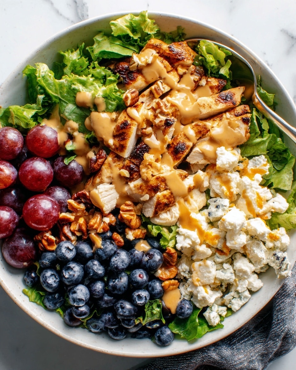 A white bowl sits on a white marbled surface, filled with a colorful mix of food arranged in sections. Starting from one side, there are fresh green lettuce leaves with a slightly rough texture. Next to it, there is a cluster of dark blue, plump blueberries with a smooth surface. Beside the blueberries, there is a creamy white layer mixed with bits of orange, showing a soft texture. Adjacent to this, there are crispy golden brown pieces covered in a drizzle of light brown sauce, adding a glossy finish. On the opposite side, a small bunch of shiny red grapes adds a juicy look. The bowl holds a balanced and vibrant combination of colors and textures. A spoon rests inside the bowl. Photo taken with an iphone --ar 4:5 --v 7