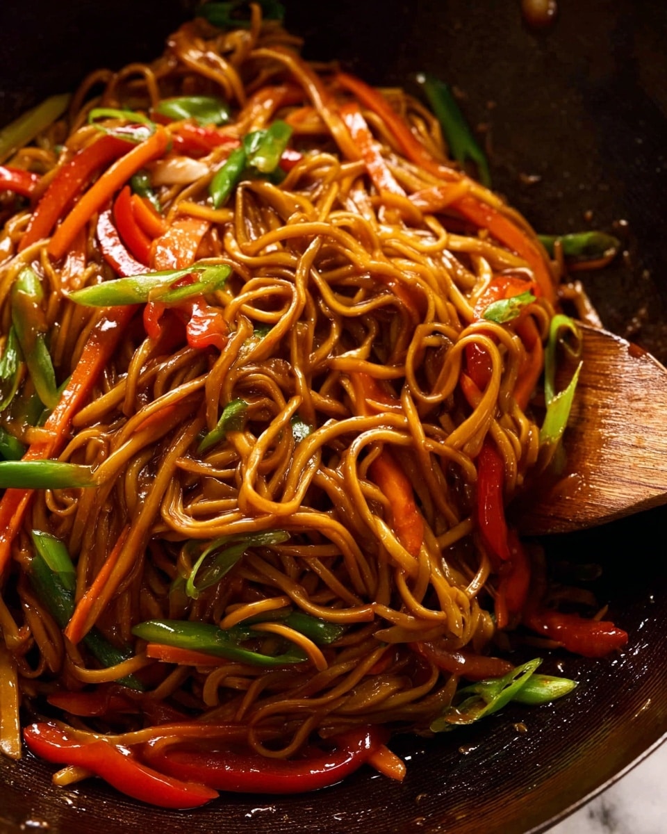 A close-up view of three layers of stir-fried noodles with a glossy brown sauce, thin orange carrot strips, and bright red bell pepper slices mixed throughout. Green strips of scallions are scattered on top, adding fresh color to the mostly warm brown and orange noodle base. The dish sits in a dark wok with a wooden spatula partly visible on the right side, blending softly into the noodles and vegetables. The surface beneath is a white marbled texture. photo taken with an iphone --ar 4:5 --v 7