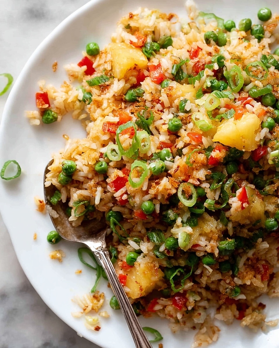 The image shows a close-up of a white plate filled with fried rice that has three main layers: the base layer consists of golden-brown cooked rice, the second layer has bright yellow pineapple chunks scattered evenly throughout, and the top layer is made up of small, colorful diced red bell peppers, green peas, and thinly sliced green onions adding fresh green and red specks on the dish. There is a spoon tucked into the rice on the right side of the plate and some grains spilled on the plate’s edge. The background features a white marbled texture. photo taken with an iphone --ar 4:5 --v 7